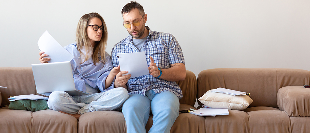 Man and woman couple reviewing documents while sitting on couch