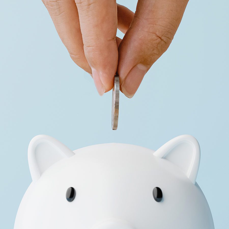 Hand Putting Coin Into Piggy Bank