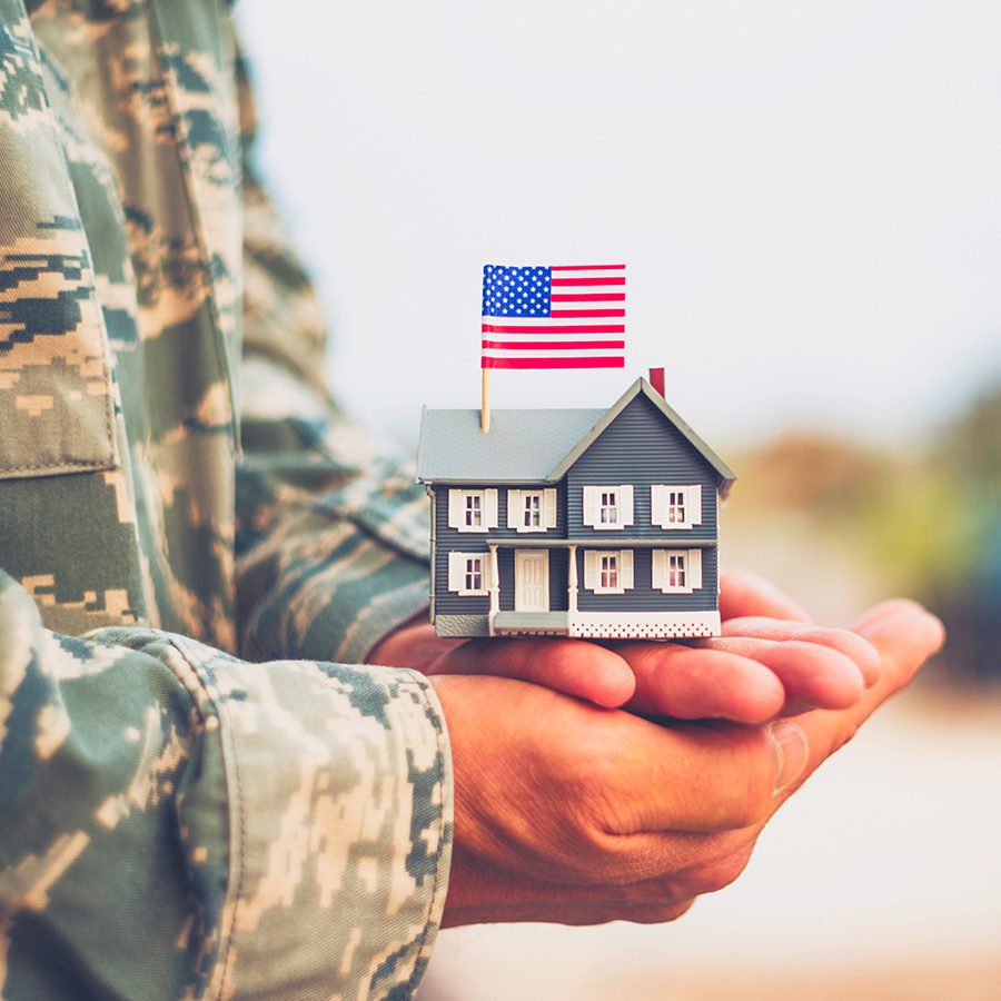 Veteran Holding a Home with American Flag on Top