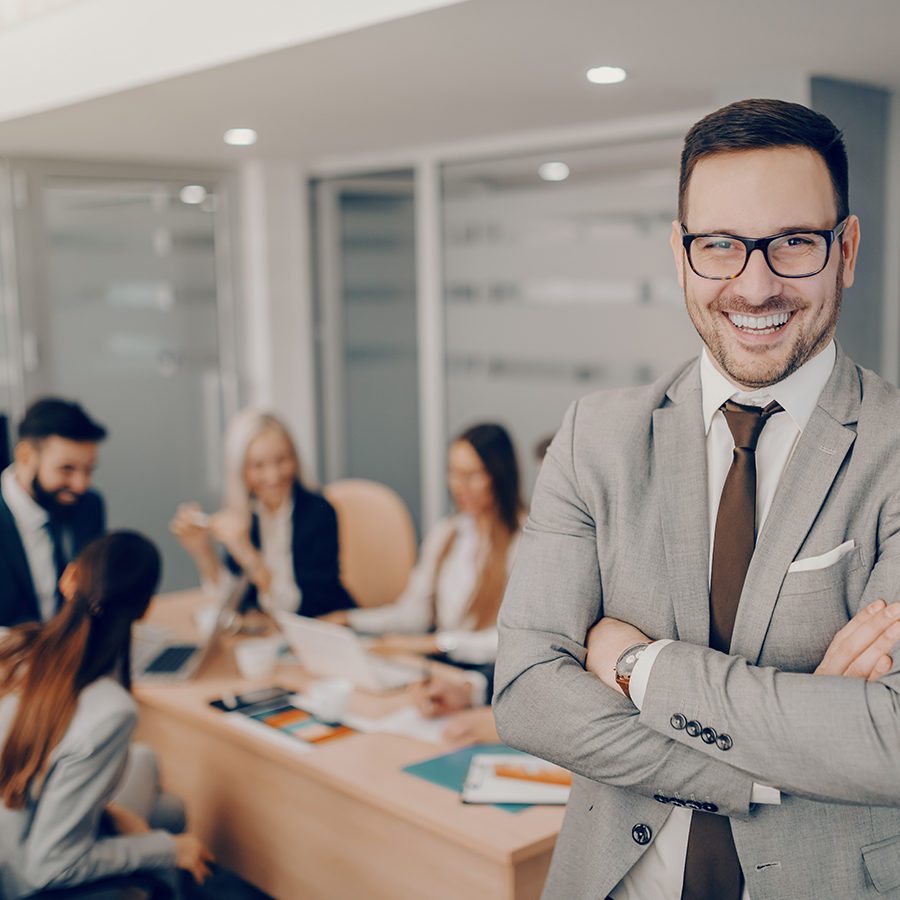 Young Business Man Smiling With Team in Background