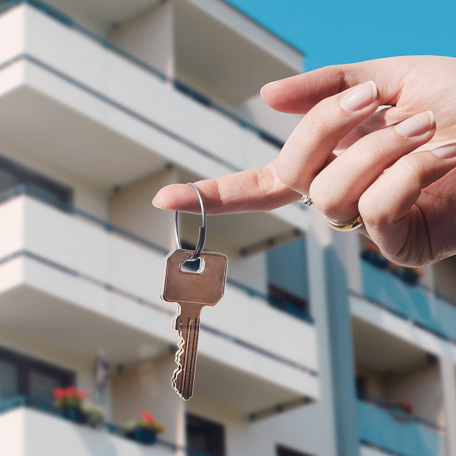 Holding Key in Front of a Condo Building