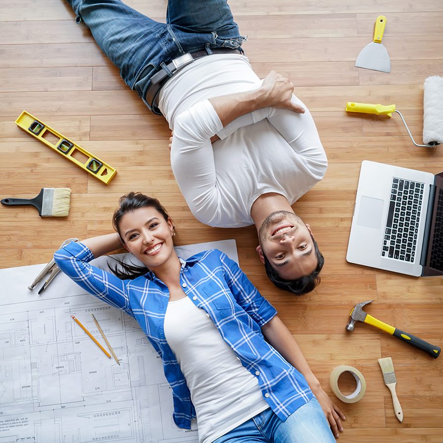 Couple Smiling on Floor With Tools for Renovating