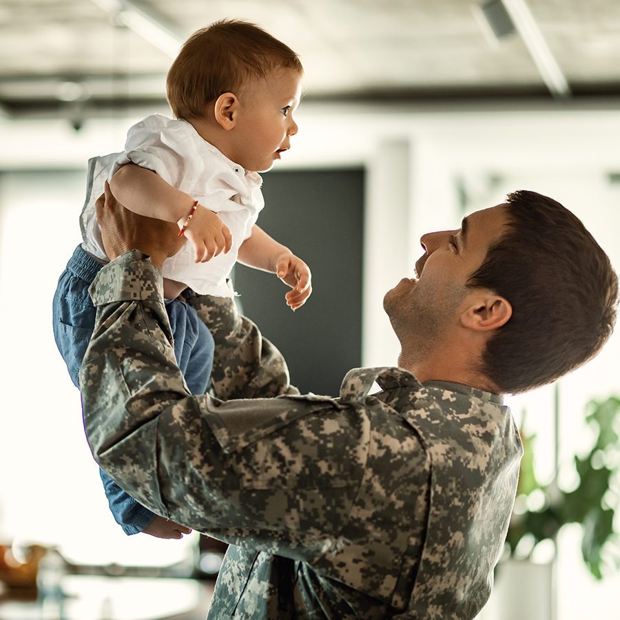 Soldier Raising Baby Son in the Air Happily