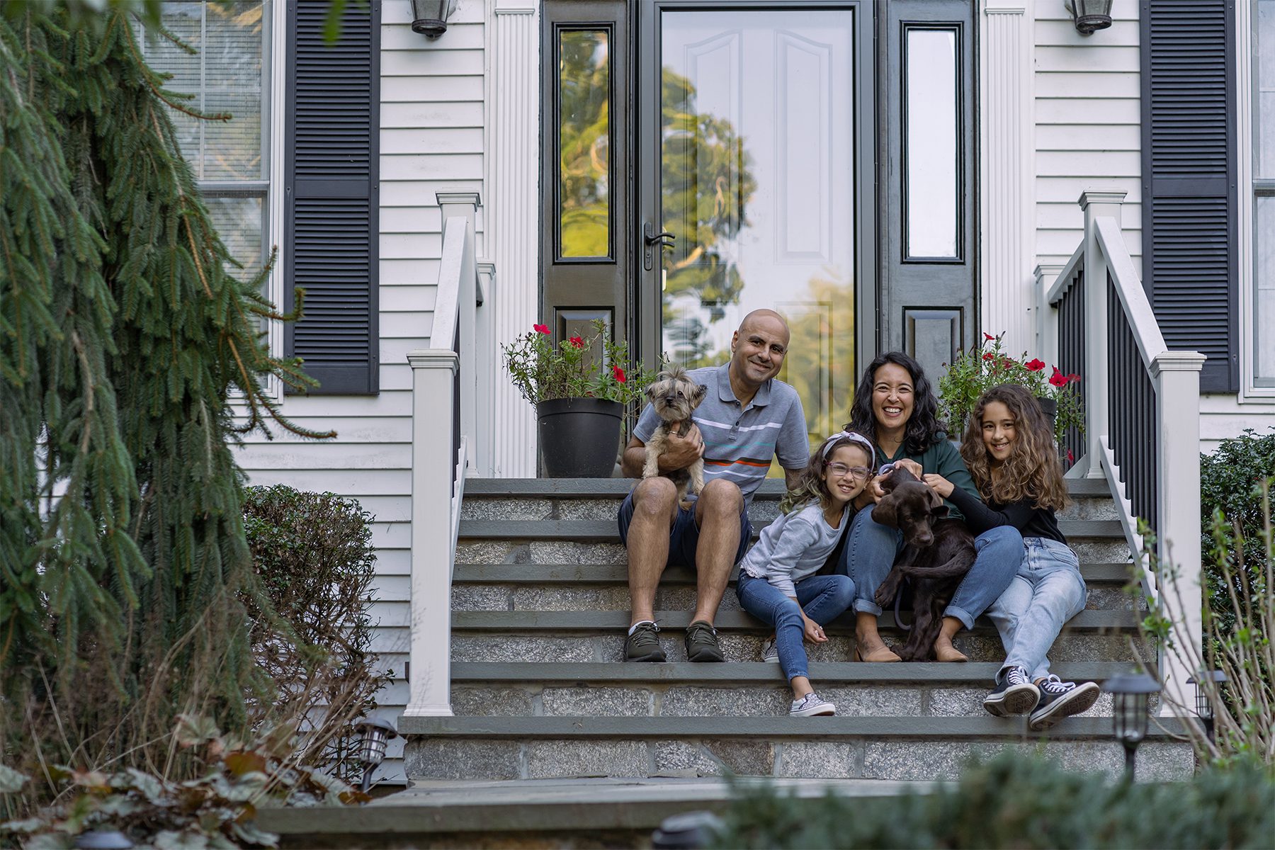 Happy Family Sitting Together on Front Steps of Their Home