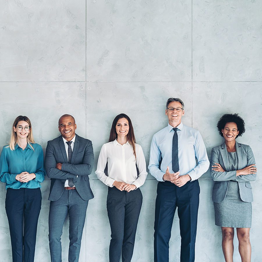 Group of Employees Smiling Together Leaning Against a Wall