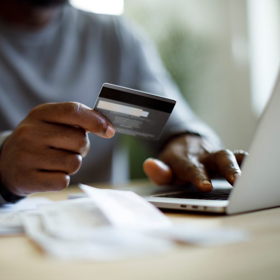 Man Holding Credit Card Near Laptop