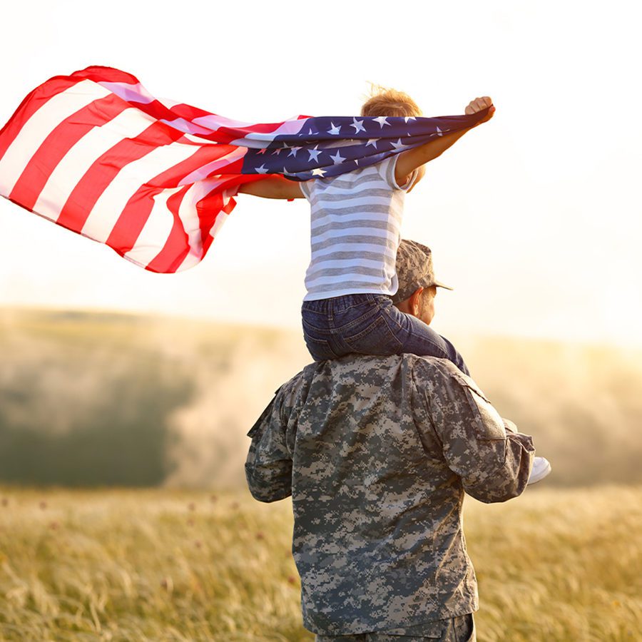 Soldier With Son Holding American Flag on Shoulders