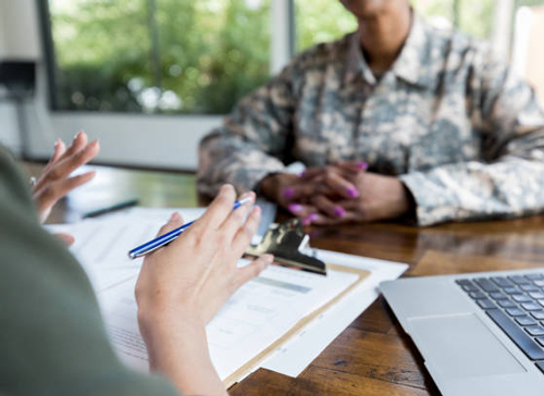 Military listening to an explanation across a table, going over paperwork. The Federal Savings Bank.