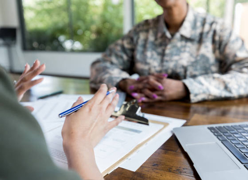 Military listening to an explanation across a table, going over paperwork. The Federal Savings Bank.