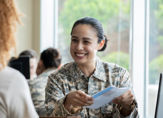 military woman smiles while holding a brochure in her handspaperwork