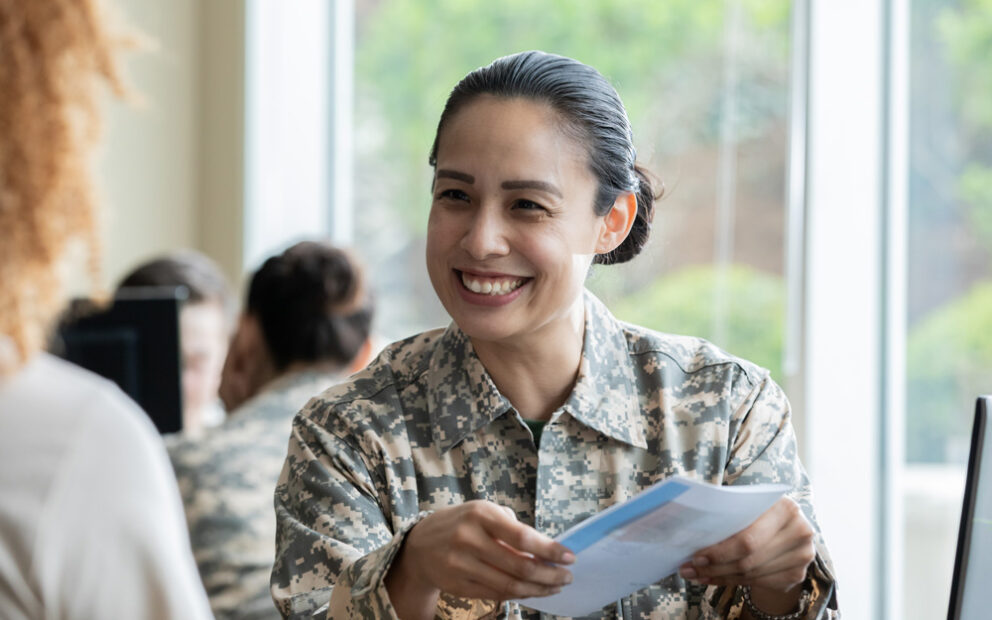 military woman smiles while holding a brochure in her handspaperwork