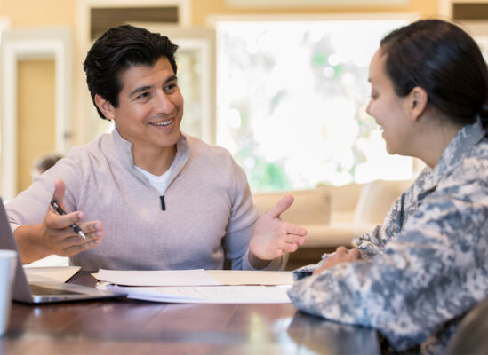 Two people smiling while having a conversation over some paperwork.