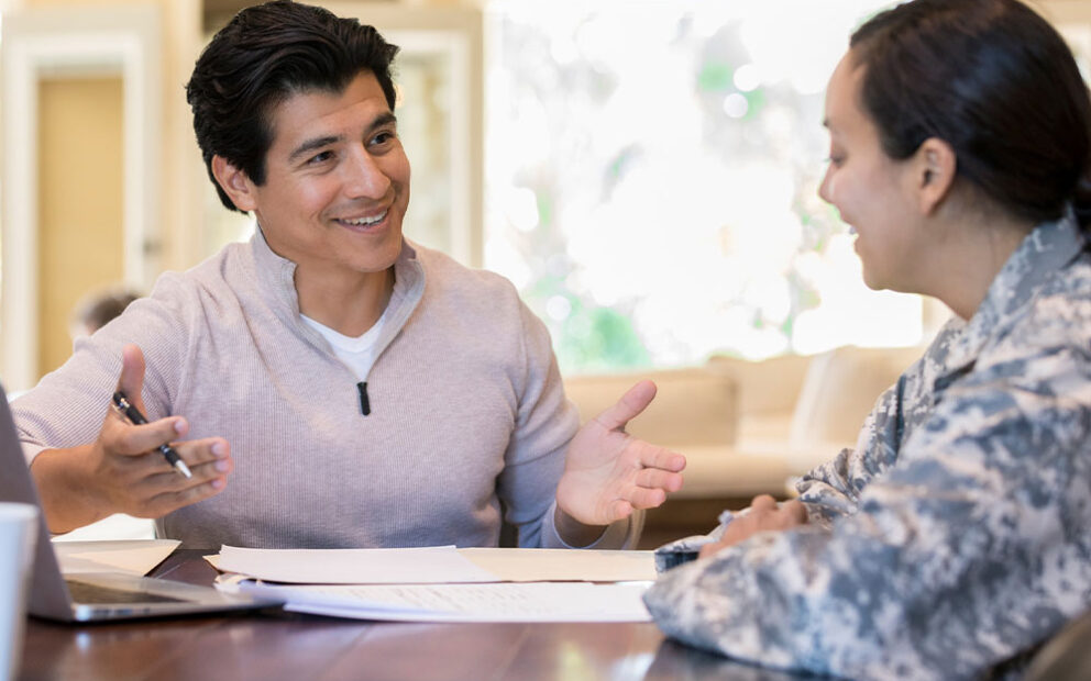 Two people smiling while having a conversation over some paperwork.