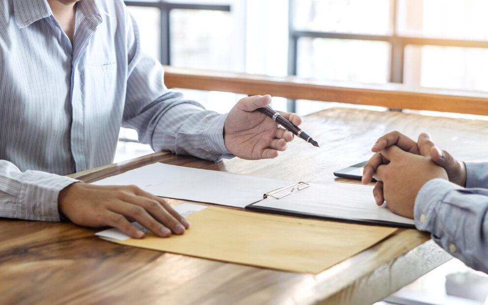 Two people discussion paperwork over a table
