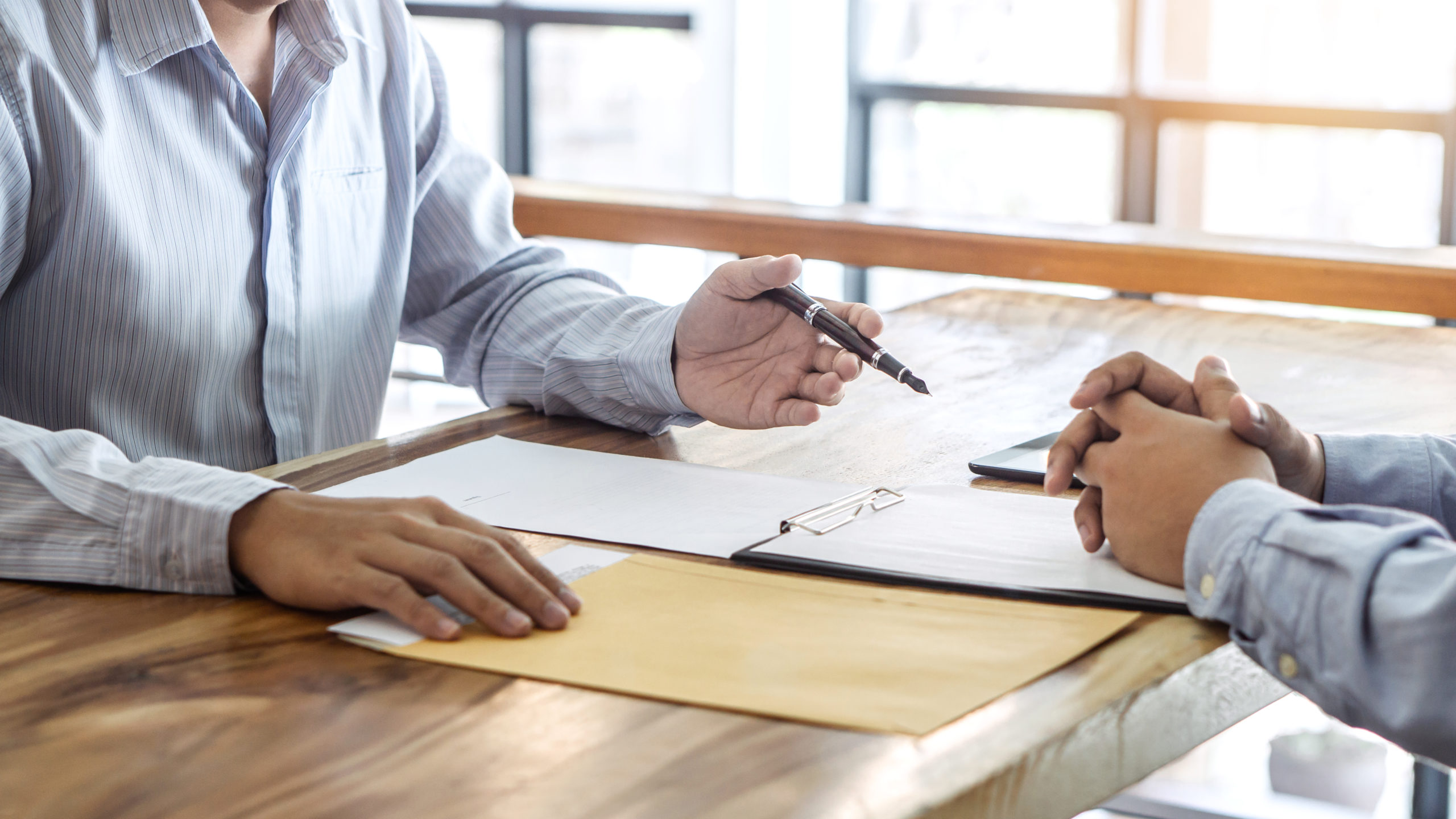 Two people discussion paperwork over a table