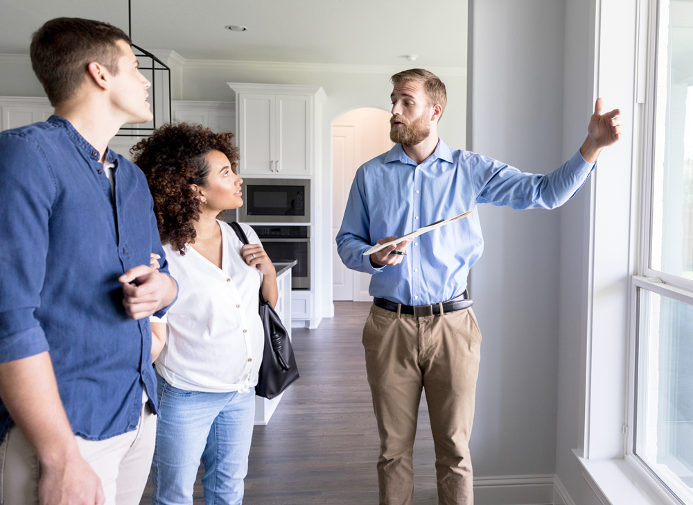 couple engaged in conversation with a man in an empty area of a home