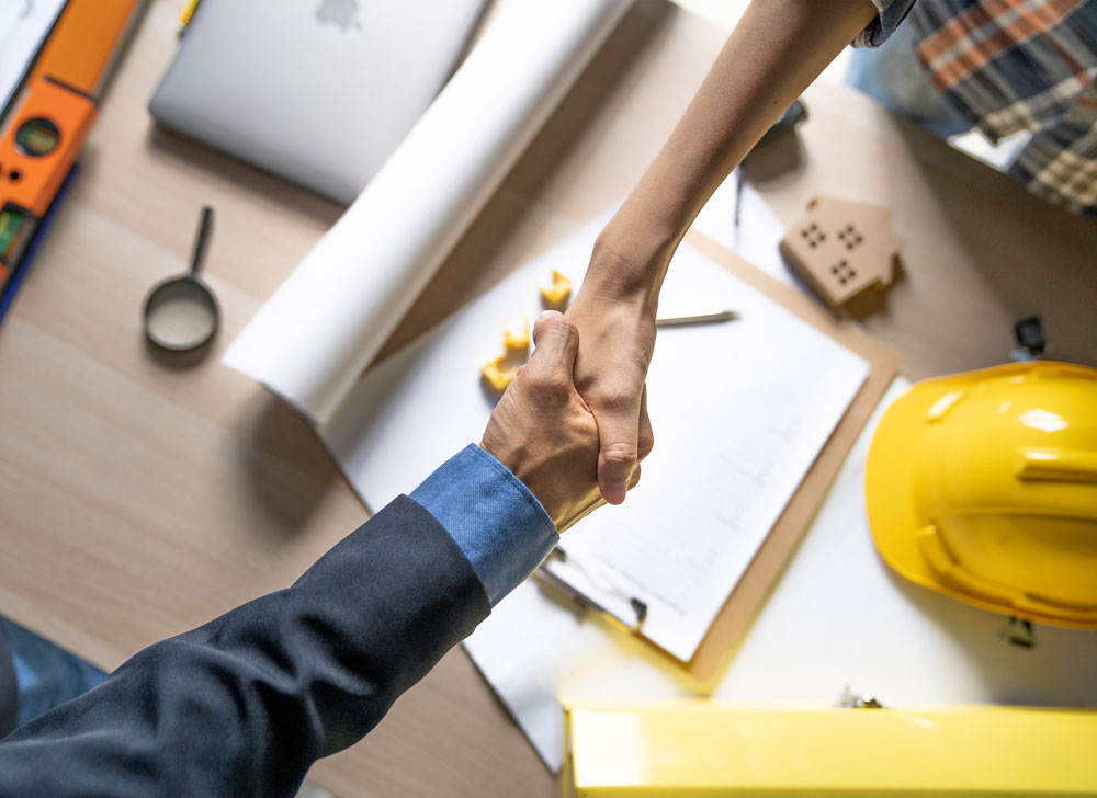 people shaking hands over a table with paperwork