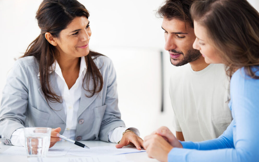 three people discussing paperwork over a table