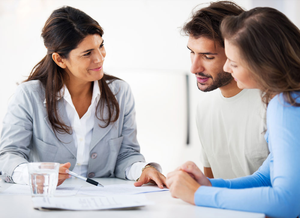 three people discussing paperwork over a table