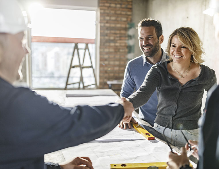 Couple shaking hands with construction worker and loan officer