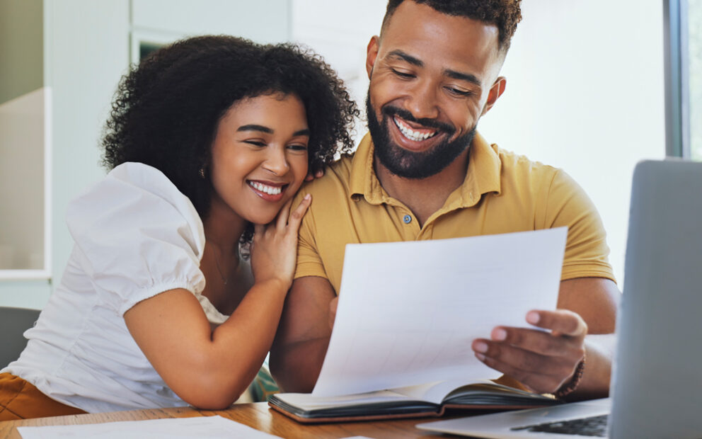 A man and a woman looking at a piece of paper and smiling