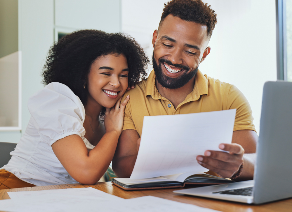 A man and a woman looking at a piece of paper and smiling