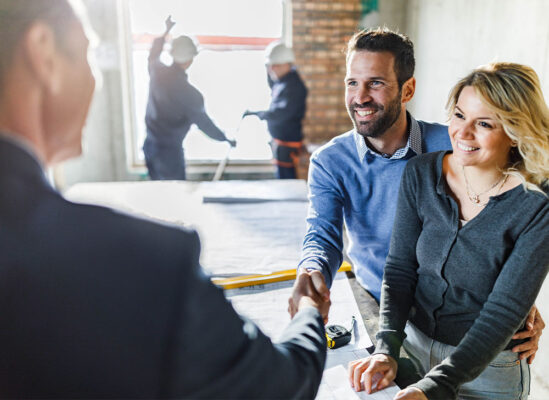 couple shaking hands with a person over a table