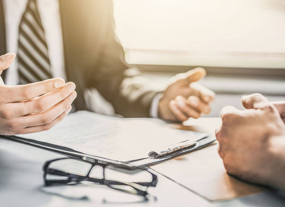 human hands on the air, over a table by some paperwork and glasses