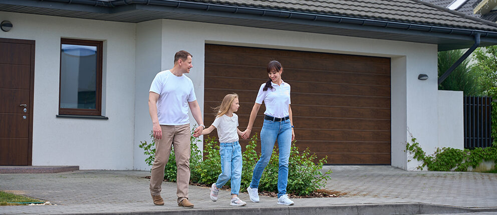 Couple holding hands with child outside new home