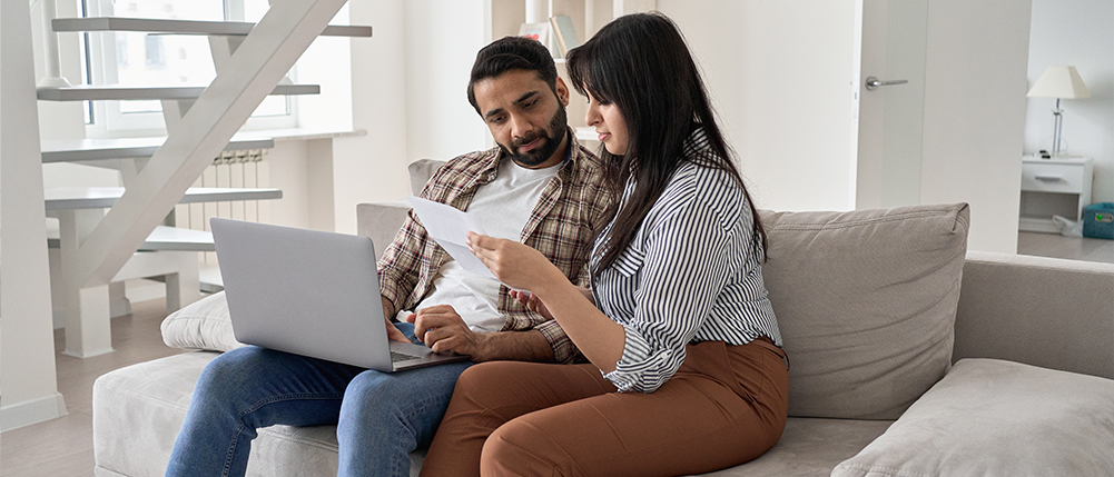Man and woman couple reviewing documents while sitting on couch
