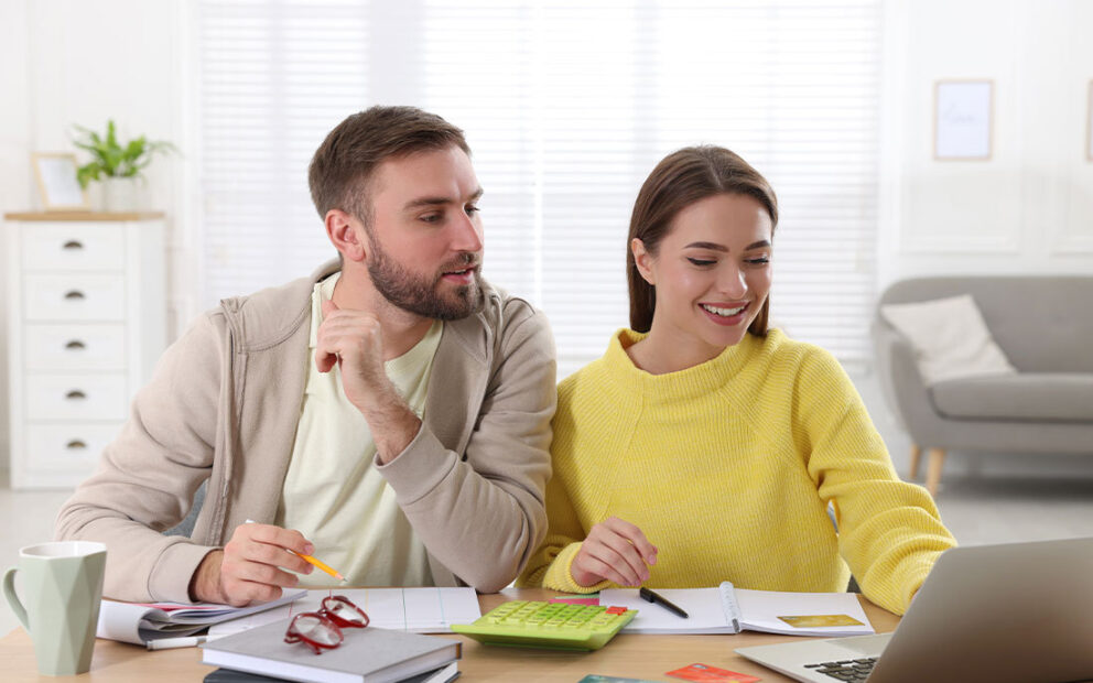Couple looking at computer, working through their finances.