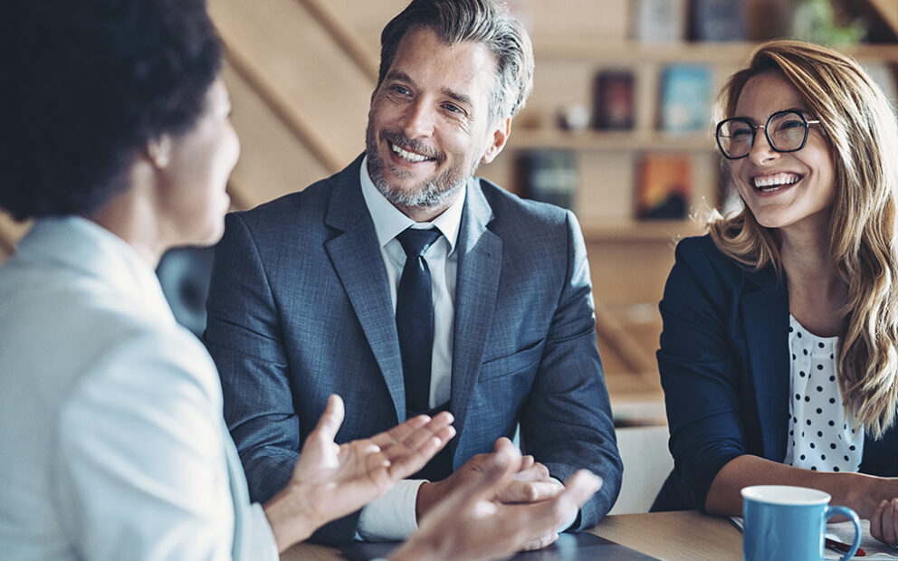 Couple in a meeting, smiling and talking with a business woman.