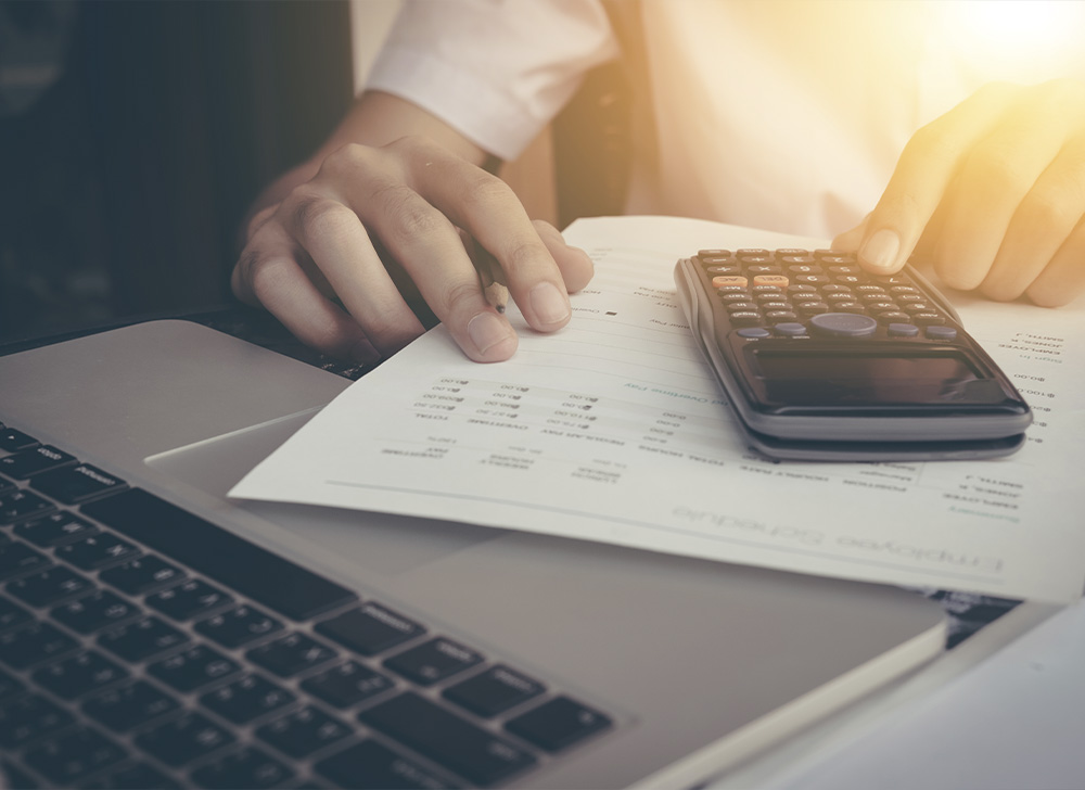 Businessman calculating numbers with calculator and laptop.