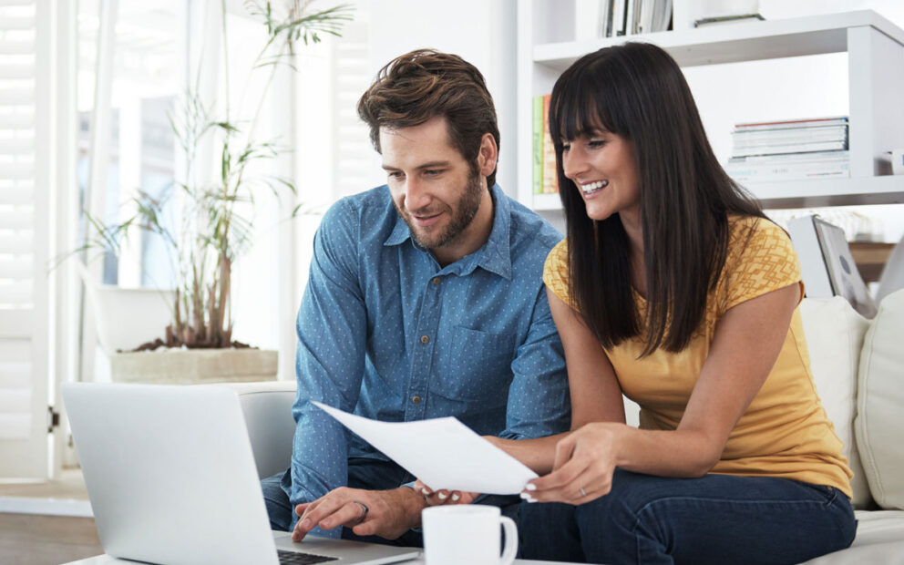 Young couple sitting on couch working on a laptop.