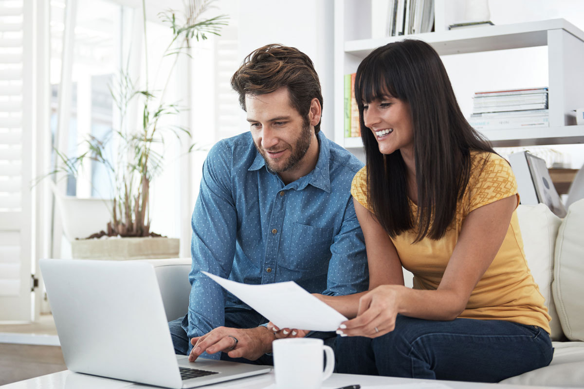 Young couple sitting on couch working on a laptop.