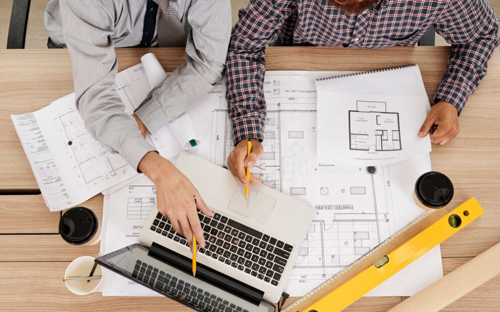 Two men looking over blueprints at a construction site.