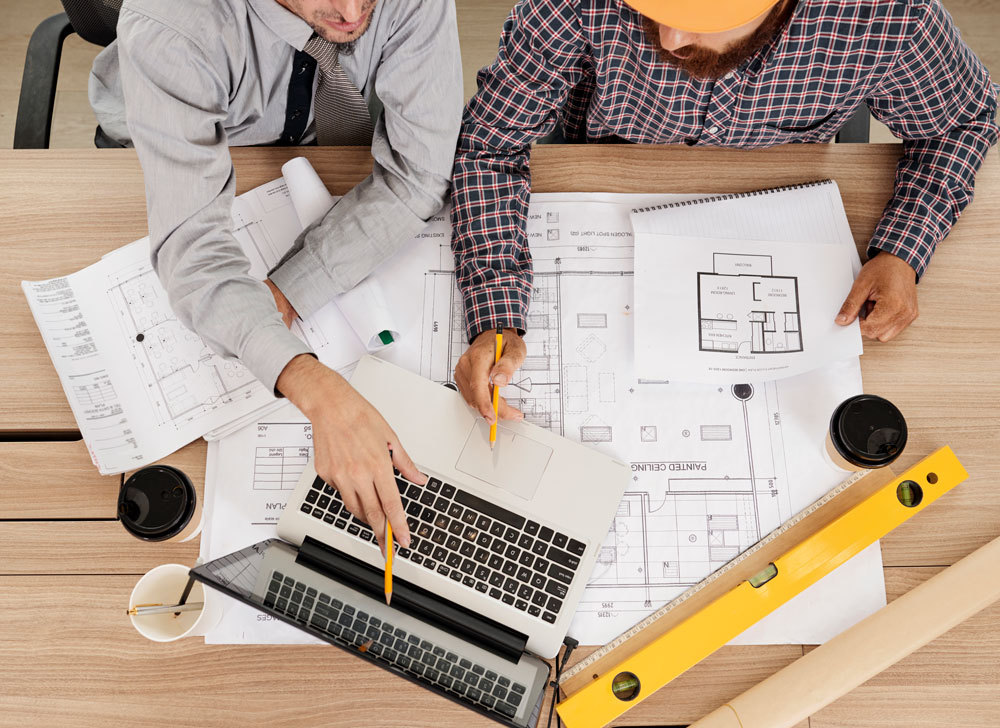 Two men looking over blueprints at a construction site.