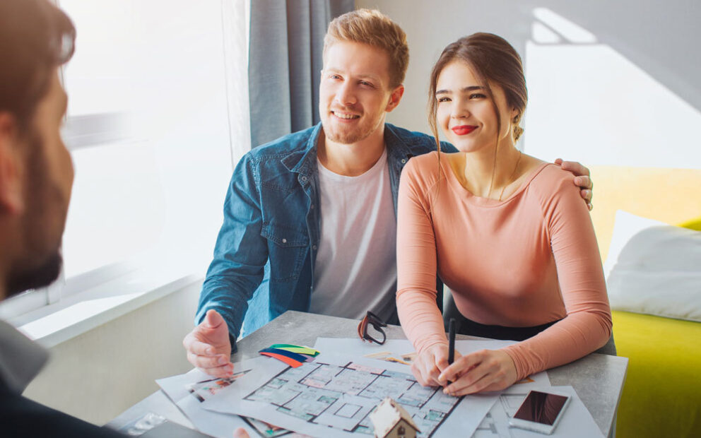 Young couple talking with their developer and looking at blueprints of their future home.