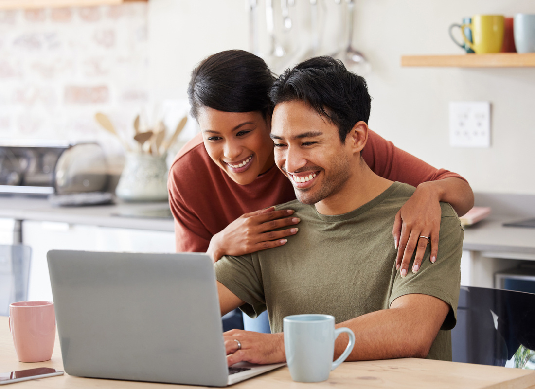 happy couple looking at a laptop together in the kitchen
