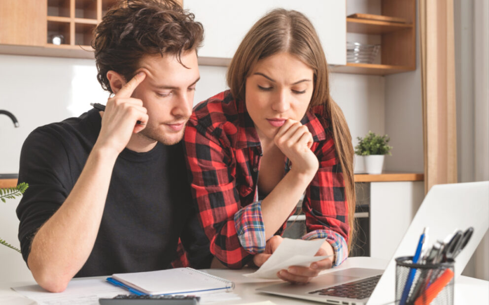 Young couple looking through their finances at the kitchen counter