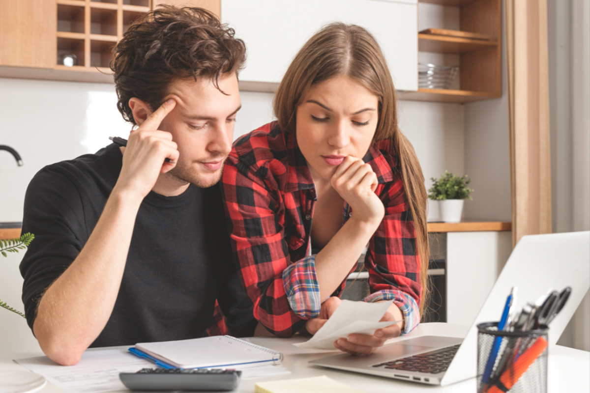 Young couple looking through their finances at the kitchen counter