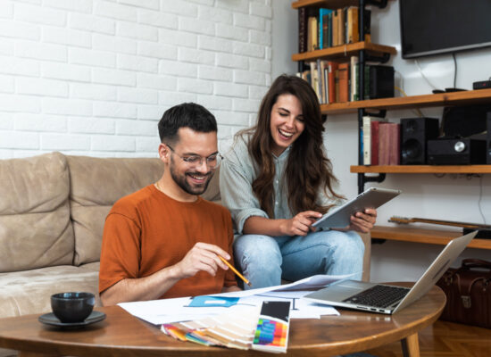 Happy couple working on their finances together in their living room.