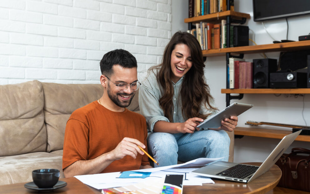 Happy couple working on their finances together in their living room.
