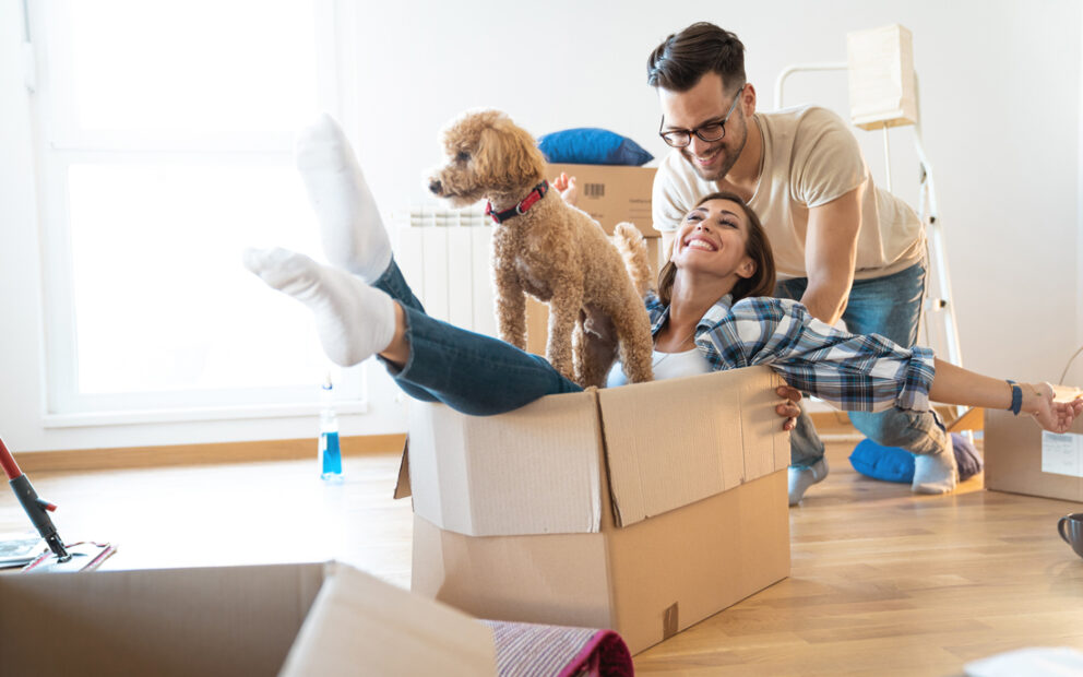 Happy couple moving into new home with their puppy.