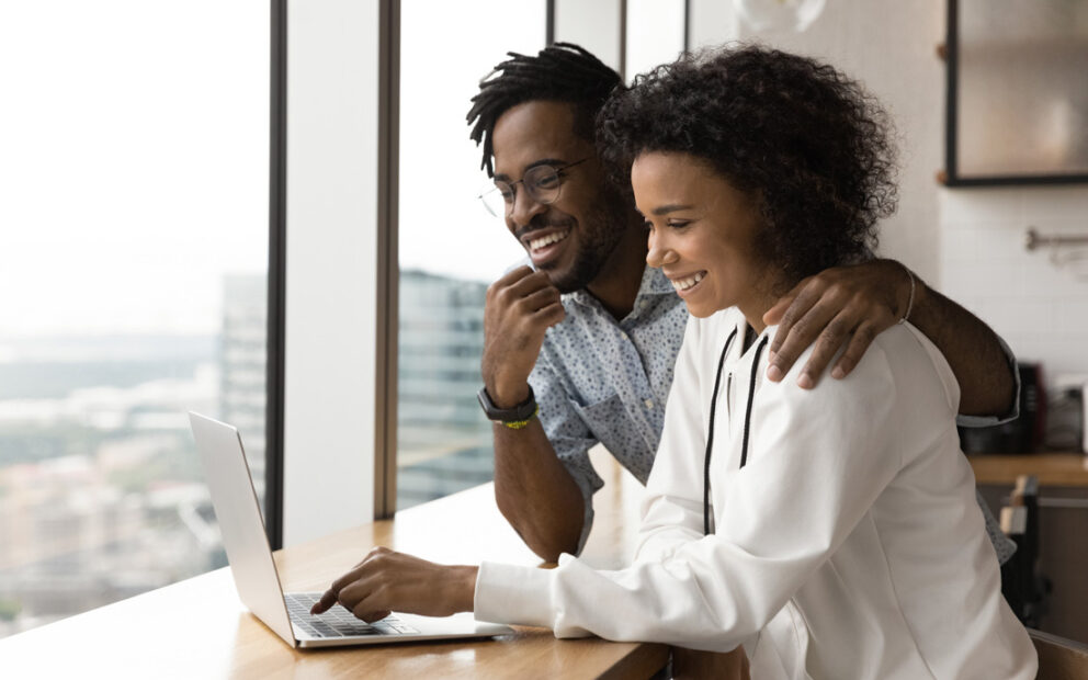 Young happy couple looking at something on a laptop together.