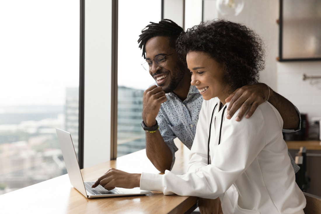 Young happy couple looking at something on a laptop together.