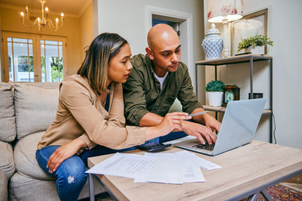 Young couple reviewing their financials on their computer in their living room.