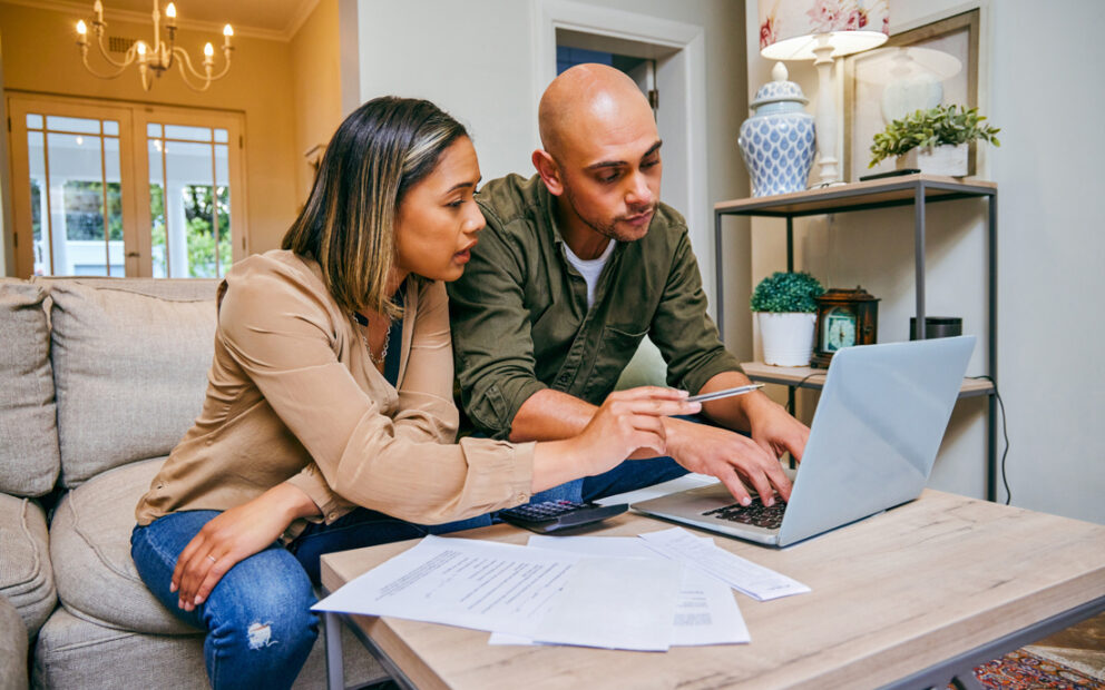 Young couple reviewing their financials on their computer in their living room.