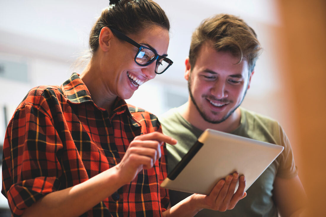 Couple looking excitedly at something on their tablet together