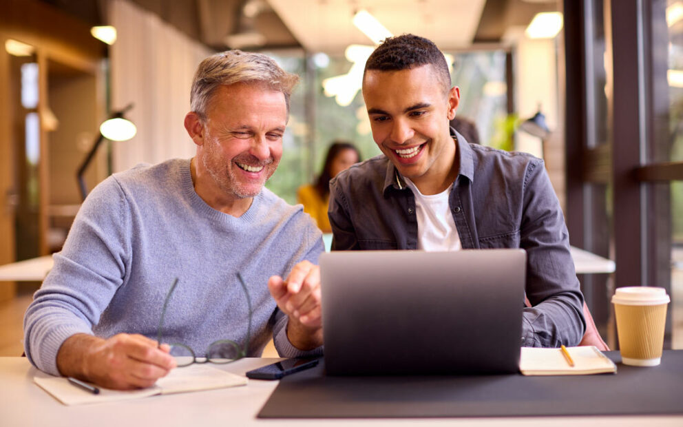 Two men working on something on a laptop together